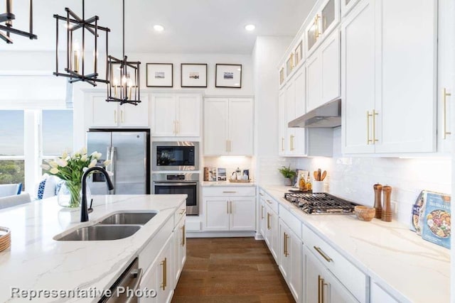 kitchen with sink, light stone counters, pendant lighting, stainless steel appliances, and white cabinets