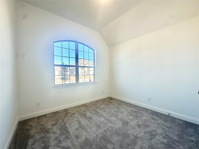 carpeted spare room with vaulted ceiling