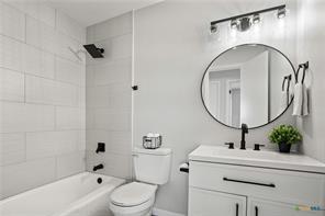 full bathroom with vanity, tiled shower / bath combo, and toilet