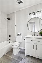 full bathroom with vanity, tiled shower / bath, hardwood / wood-style flooring, and toilet