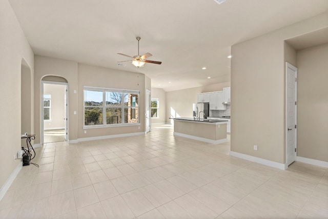 unfurnished living room with vaulted ceiling, ceiling fan, and light tile patterned flooring