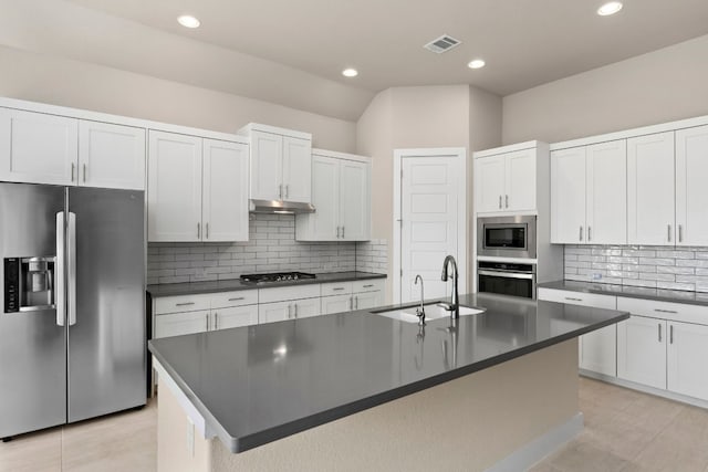 kitchen with an island with sink, appliances with stainless steel finishes, sink, and white cabinets