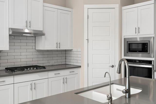 kitchen with white cabinetry, appliances with stainless steel finishes, sink, and backsplash