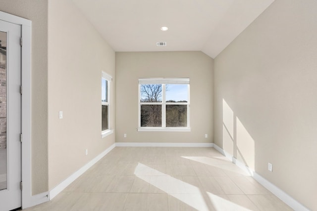 empty room featuring vaulted ceiling and light tile patterned floors