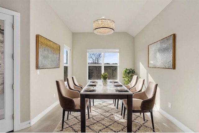 tiled dining area featuring an inviting chandelier and vaulted ceiling