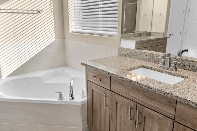 bathroom featuring a relaxing tiled tub and vanity