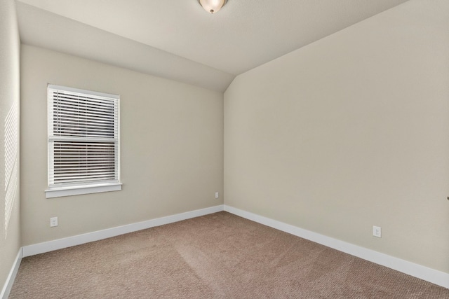 carpeted empty room featuring lofted ceiling