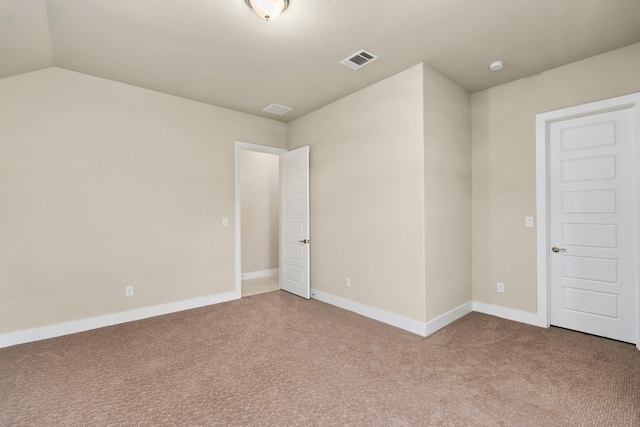 carpeted empty room featuring lofted ceiling