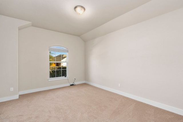 carpeted empty room featuring vaulted ceiling