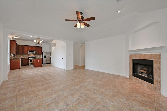 10104 Hibiscus Cv, Austin, TX 78739 - unfurnished living room featuring arched walkways, a chandelier, a tiled fireplace, a ceiling fan, and a sink