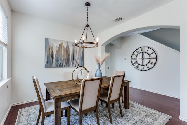 dining space featuring visible vents, baseboards, arched walkways, a chandelier, and wood finished floors