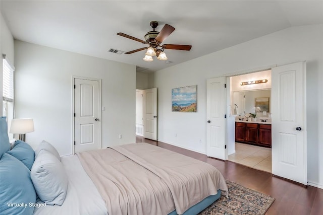 bedroom featuring baseboards, ensuite bath, light wood-style floors, visible vents, and ceiling fan