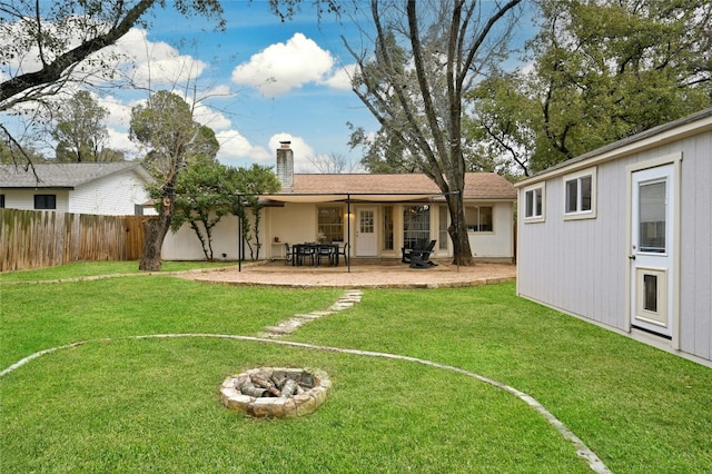 rear view of property with an outdoor fire pit and a yard