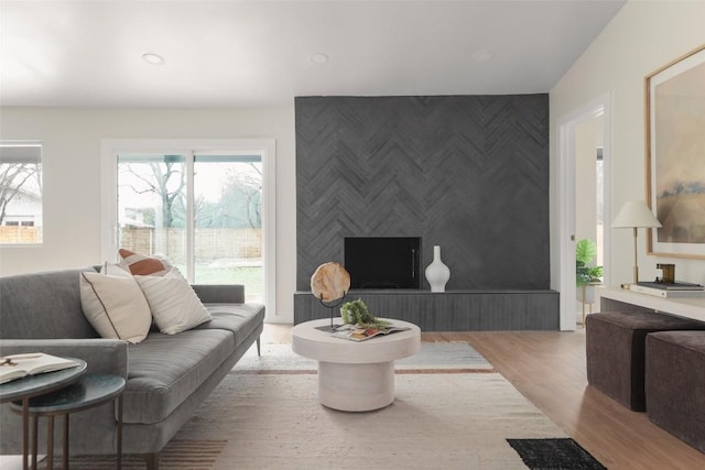 living area featuring a wealth of natural light, recessed lighting, an accent wall, and wood finished floors