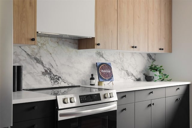 kitchen featuring stainless steel range with electric cooktop, under cabinet range hood, light countertops, backsplash, and gray cabinets