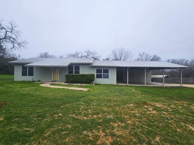 back of property with a carport and a lawn