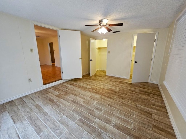 spare room with ceiling fan, a textured ceiling, and light wood-type flooring