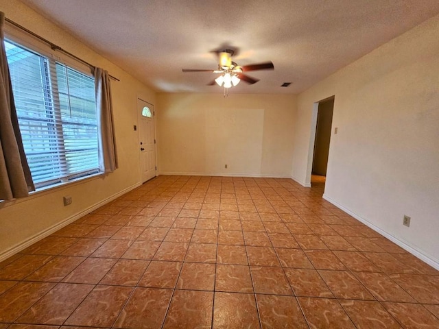 tiled empty room featuring a textured ceiling and ceiling fan