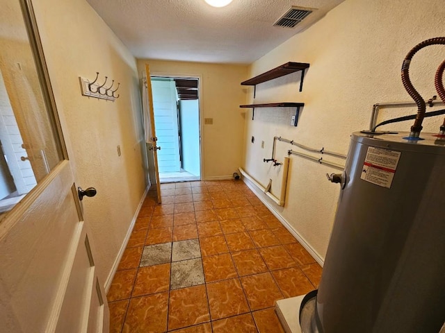 hall with gas water heater, tile patterned floors, and a textured ceiling