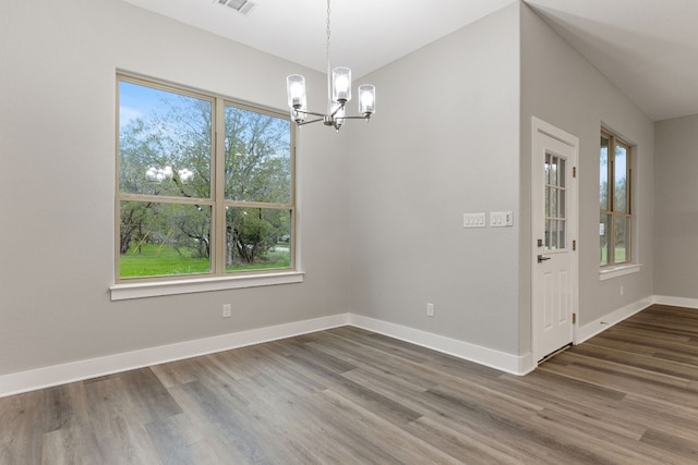 unfurnished dining area with dark wood-type flooring and an inviting chandelier