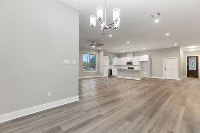 unfurnished living room with ceiling fan with notable chandelier and light hardwood / wood-style floors