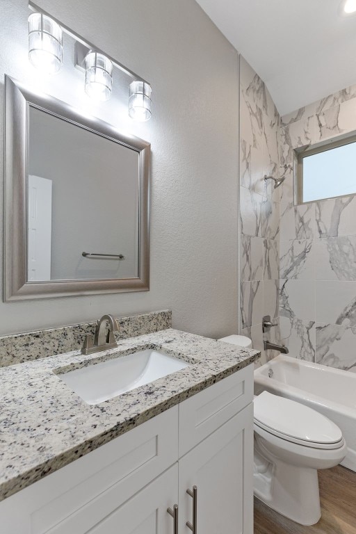 full bathroom with vanity, hardwood / wood-style flooring, toilet, and tiled shower / bath