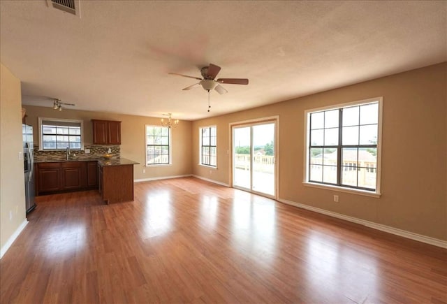 unfurnished living room with sink, dark hardwood / wood-style floors, and ceiling fan with notable chandelier