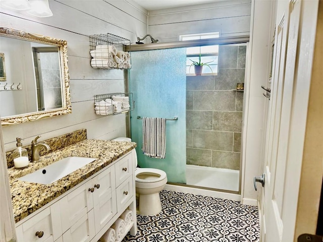 302 E Castlewood Dr, Granite Shoals, TX 78654 - bathroom featuring wood walls, a shower with shower door, tile patterned flooring, vanity, and toilet