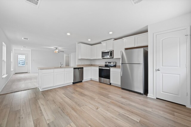 kitchen featuring sink, kitchen peninsula, white cabinets, and appliances with stainless steel finishes