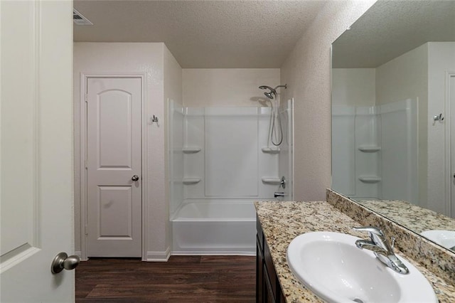 bathroom featuring vanity, hardwood / wood-style flooring, shower / bathtub combination, and a textured ceiling