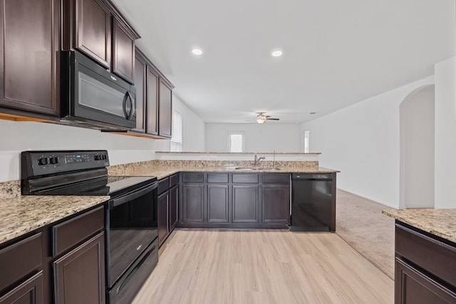 kitchen featuring sink, ceiling fan, dark brown cabinetry, light stone counters, and black appliances