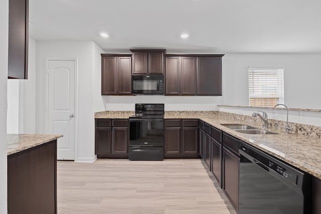 kitchen featuring light hardwood / wood-style floors, sink, light stone countertops, and black appliances