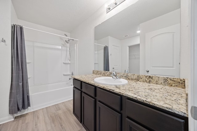 bathroom featuring shower / tub combo with curtain, wood-type flooring, vanity, and a textured ceiling