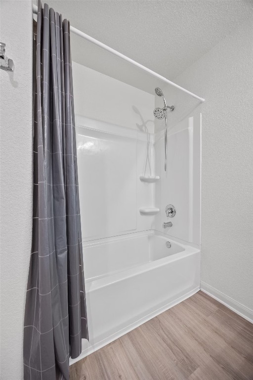 bathroom with wood-type flooring and shower / bathtub combination with curtain