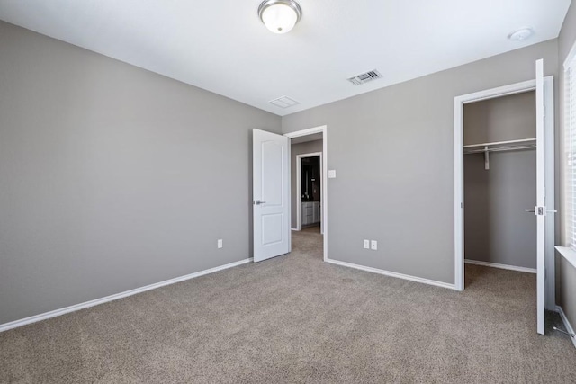 unfurnished bedroom with a spacious closet, a closet, and carpet