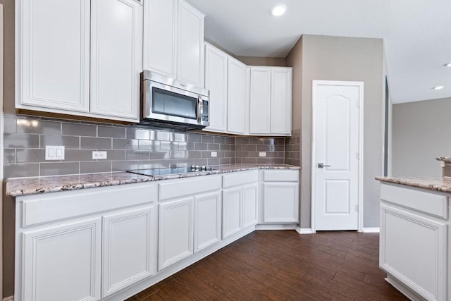 kitchen featuring white cabinetry, backsplash, dark hardwood / wood-style flooring, black electric stovetop, and light stone counters