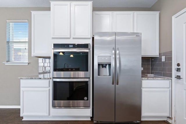 kitchen featuring white cabinetry, light stone countertops, backsplash, and stainless steel appliances