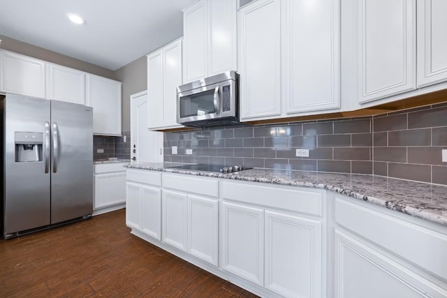 kitchen with dark wood-type flooring, light stone counters, stainless steel appliances, decorative backsplash, and white cabinets