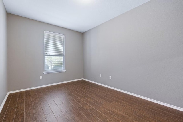 empty room with baseboards and dark wood-style flooring