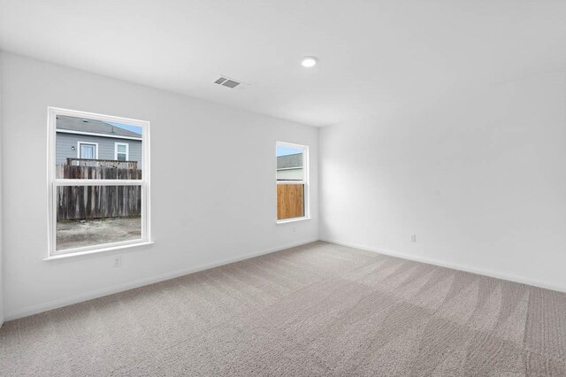 spare room with carpet, visible vents, and baseboards