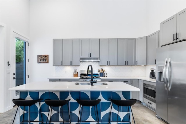 11233/4 Gunter St Unit 2, Austin, TX 78702 - kitchen with concrete flooring, a towering ceiling, gray cabinets, under cabinet range hood, and stainless steel appliances