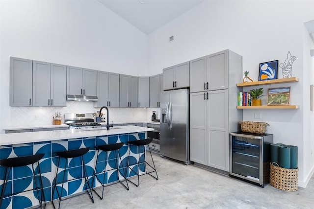 11233/4 Gunter St Unit 2, Austin, TX 78702 - kitchen with concrete floors, under cabinet range hood, stainless steel appliances, high vaulted ceiling, and beverage cooler