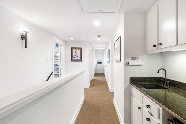 hallway featuring sink and light carpet