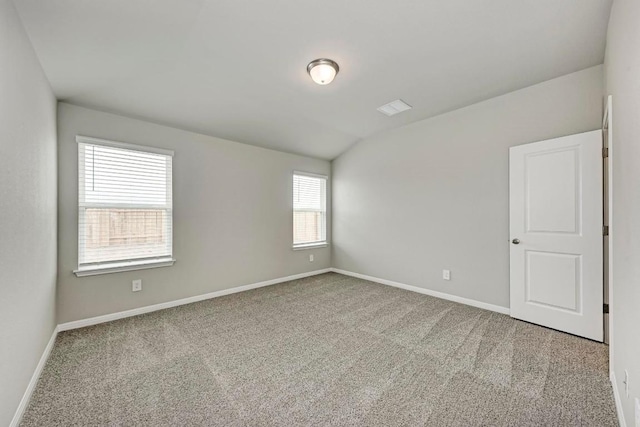 carpeted spare room featuring lofted ceiling