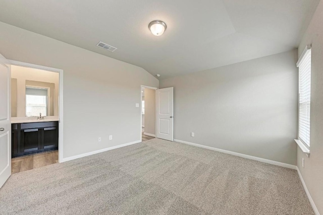 carpeted spare room with lofted ceiling, plenty of natural light, and sink