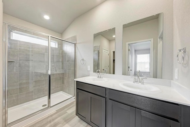 bathroom with vanity, hardwood / wood-style floors, vaulted ceiling, and a shower with door