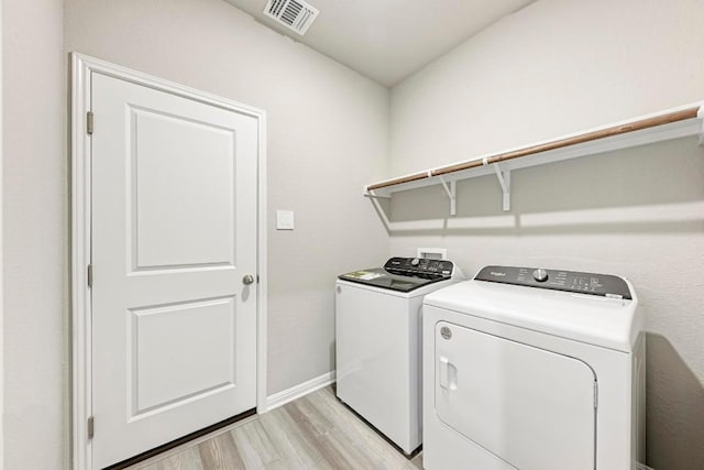 clothes washing area featuring washing machine and dryer and light wood-type flooring