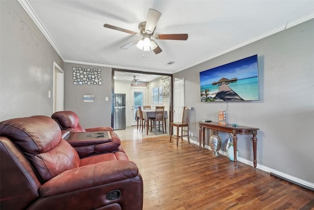 living room with wood-type flooring, ornamental molding, and ceiling fan