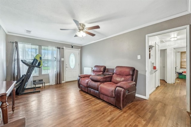 living room featuring hardwood / wood-style flooring, ceiling fan, crown molding, and a textured ceiling