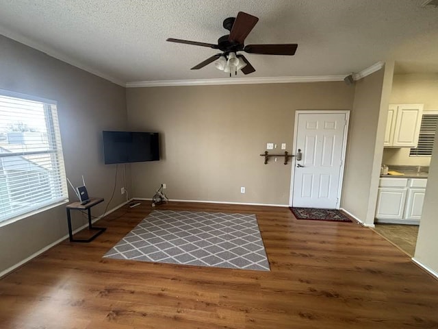 unfurnished living room featuring dark wood-type flooring, ornamental molding, and ceiling fan